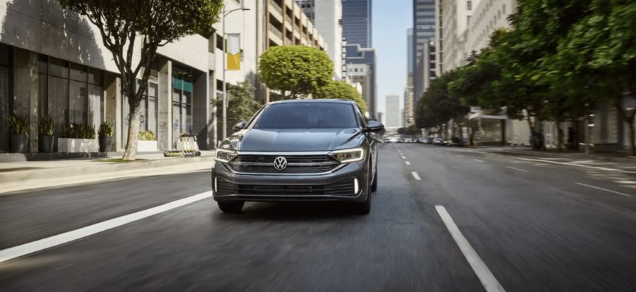 A 2024 Volkswagen Jetta compact sedan model driving through an urban city landscape