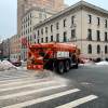 A sanitation department truck spreading road salt and and on city car roads