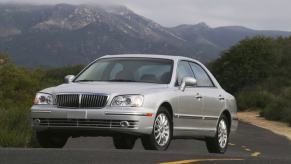 A 2004 Hyundai XG350 luxury sedan model driving in the country with a foggy mountain framed behind it