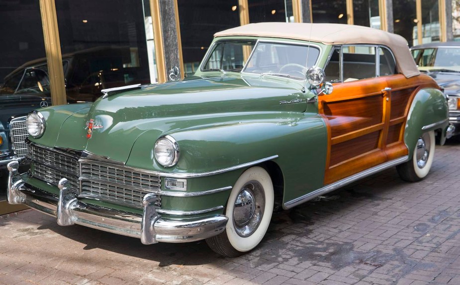 Green wood-sided classic convertible car parked on a city street.