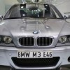 A silver used 2003 BMW E46 M3 CSL front view parked inside an auction house showroom