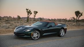 A green C7 Corvette Stingray Convertible sits on a desert road.