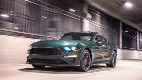 A Dark Highland Green S550 Ford Mustang Bullitt drives through a tunnel.