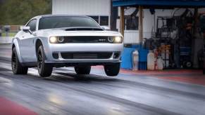 A silver and black Dodge Challenger SRT Demon 170 performance car does a wheelie.