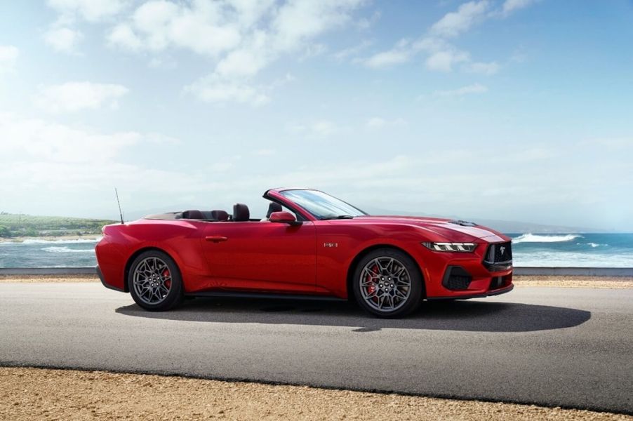 A bright-red 2024 Ford Mustang GT Convertible shows off its soft top by the coast.