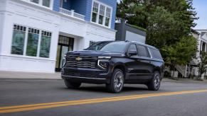 The newest Chevrolet Suburban SUV driving down main street in a small town.