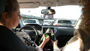 Two drivers cheer with open beers while driving a car.