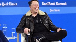 Elon Musk, head of Tesla, smiles at a event.