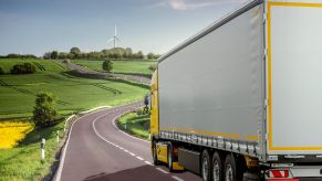 Yellow semi truck driving through the French countryside.