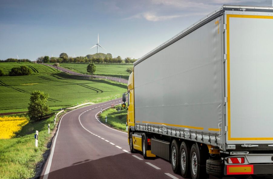 Yellow semi truck driving through the French countryside.