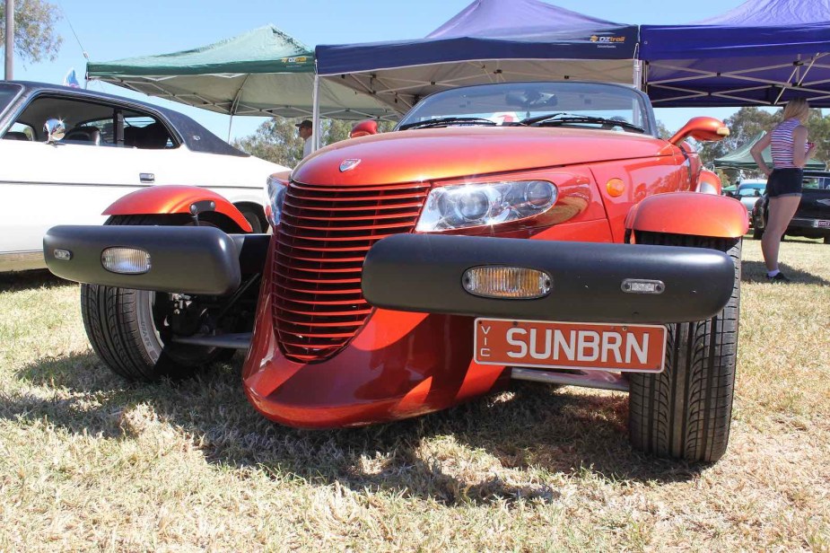 Orange sports car parked in a field during a car show.