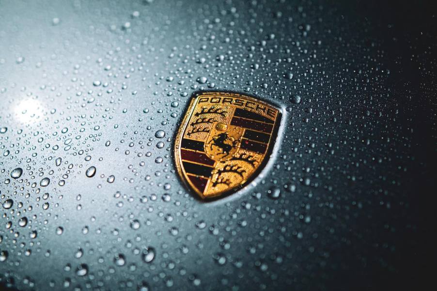 The Porsche crest logo on the hood of a gray car.