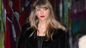 Taylor Swift leaves an event in a dark coat.