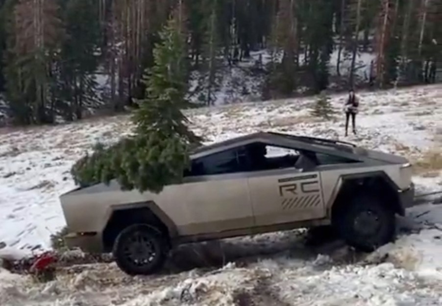 Prototype Tesla Cybertruck carrying a Christmas tree up a snowy hill.