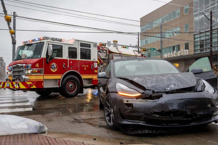 Crashed Tesla vehicle with autopilot with a firetruck visible in the background.