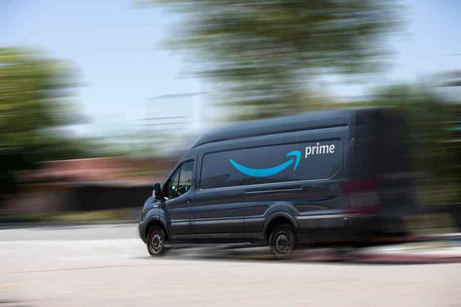 A blue Amazon Prime delivery van is shown in left side view driving fast with a blurred background