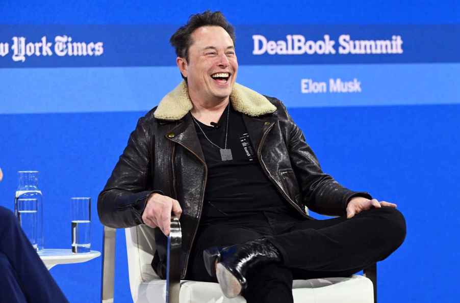 Elon Musk laughing while sitting at the 2023 New York Times DealBook Summit