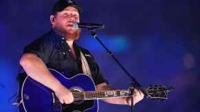 Luke Combs singing onstage while playing guitar