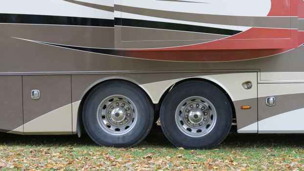 RV axles are shown in close exterior view, four RV wheels in profile view parked on grass