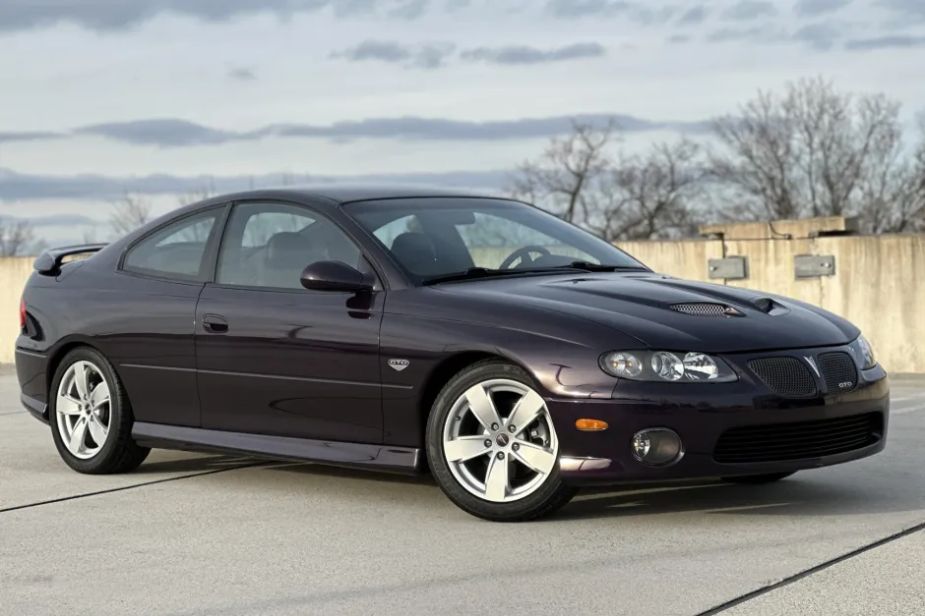 A black 2004 Pontiac GTO is parked at right front angle with a cloudy sky in the background