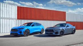 A blue Ford Mustang Mach-E and a GT Coupe park in a harbor.