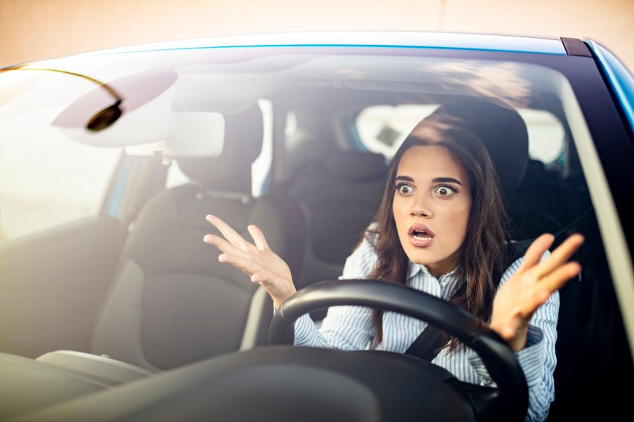 Confused woman gestures during road rage incident.