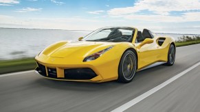 Bright yellow Ferrari convertible driving along the coast.