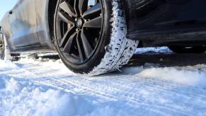 A black Ford Mustang GT sports car parks in the snow.