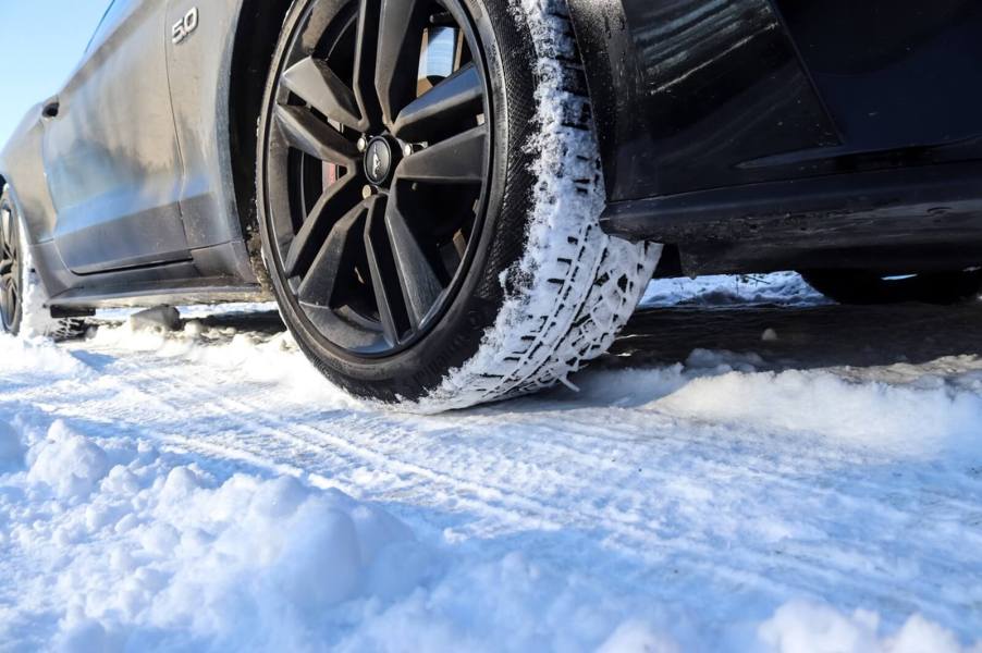 A black Ford Mustang GT sports car parks in the snow.