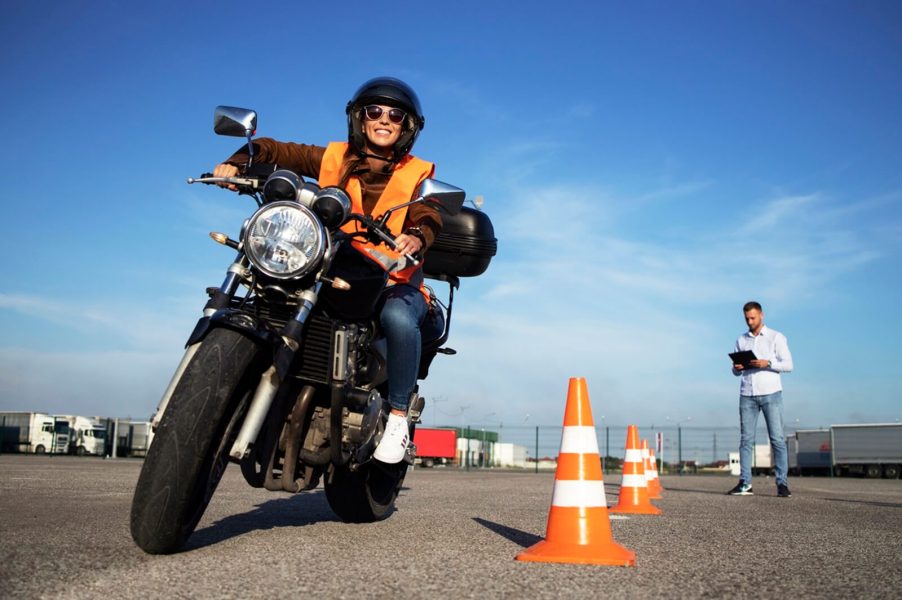 A smiling motorcycle rider takes on a course for licensing.