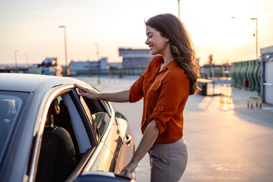 Woman stands next to a new car she's buying to check the manufacturer date