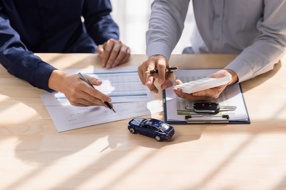 Dealership salesman and customer go through car paperwork.