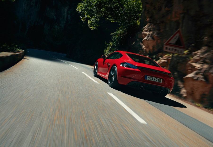 A red Porsche 718 Cayman GTS drives around a mountain road.