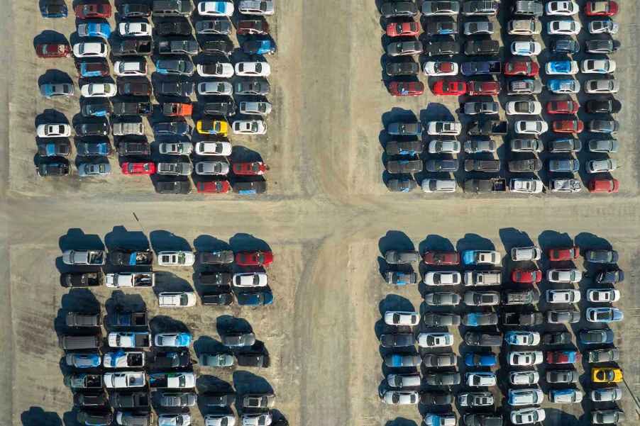 Rows of crossover SUVs and cars parked in a salvage yard.