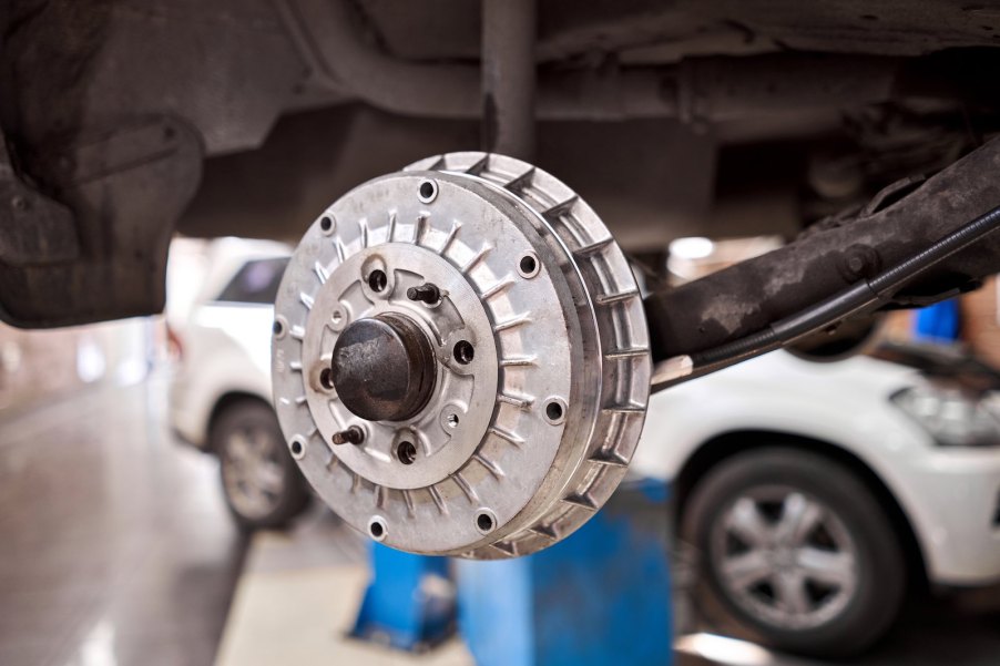 Futuristic alloy brake drum with cooling fins, attached to a car.