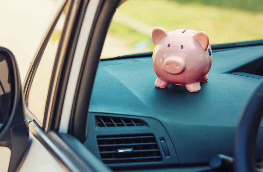 A pink piggy bank sitting on the dash of a car