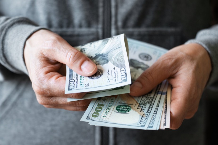 Driver holding a stack of $100 bills