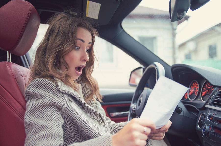 Woman stares at the contract to buy a new SUV with a destination charge.