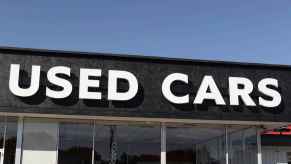 Backlit lettering spelling "Used Cars" is shown on the front of a car sales building