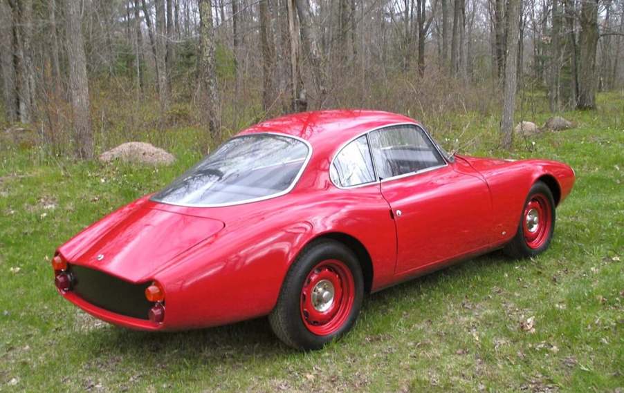 Red 1961 SSZ Stradale prototype parked in front of the woods.