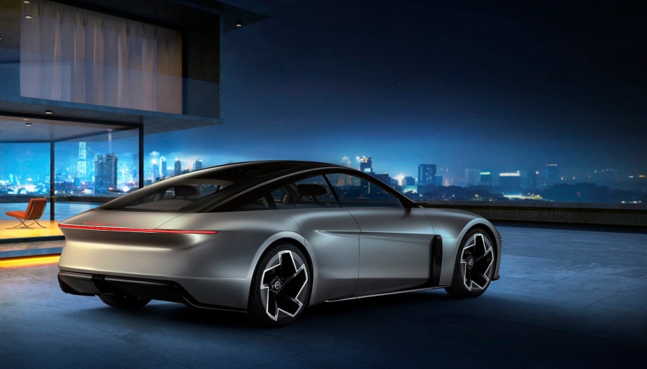 Rear of a Chrysler Halcyon concept EV parked in front of a city skyline at night.