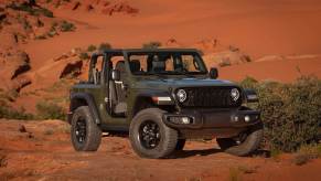 A green 2024 Jeep Wrangler JL Willys model parks without doors or a roof.