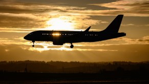 Commercial jet airplane flying in front of a sunseet.