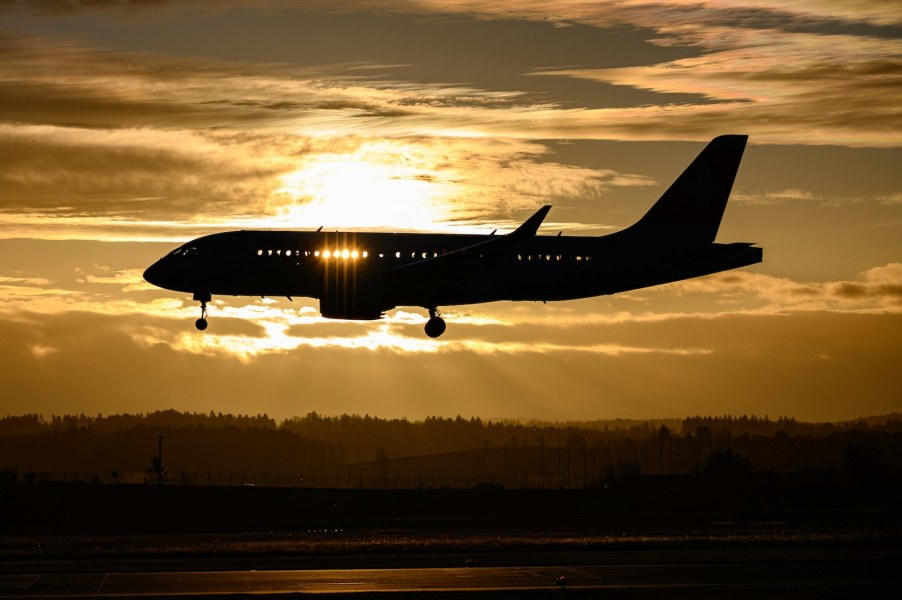 Commercial jet airplane flying in front of a sunseet.