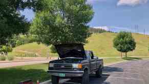 Black Ford F-150 pickup truck in a parking lot with its hood up for maintenance.