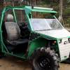 Green UTV side-by-side assembled with old car parts parked in the woods.