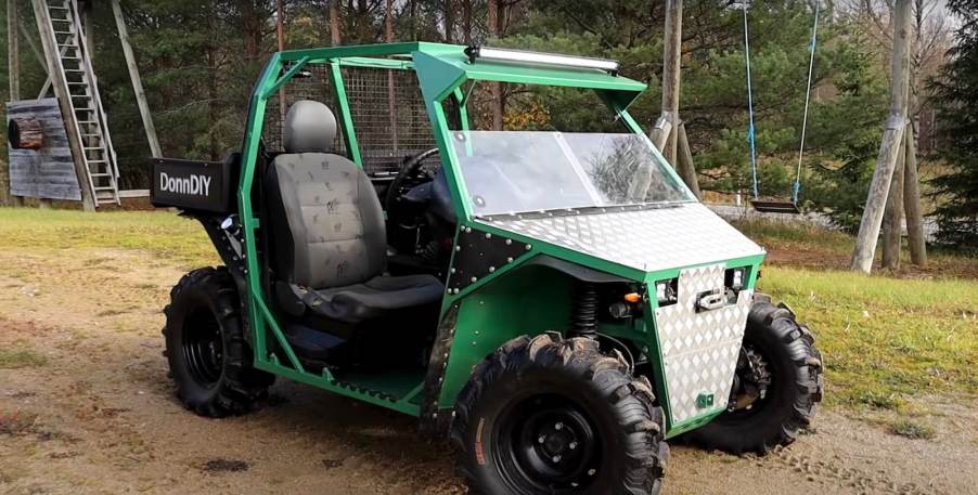 Green UTV side-by-side assembled with old car parts parked in the woods.