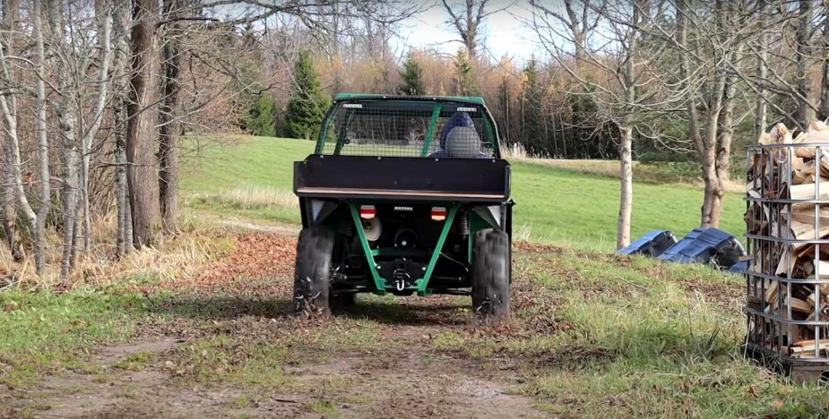 Homemade side-by-side driving down a two-track in a field.