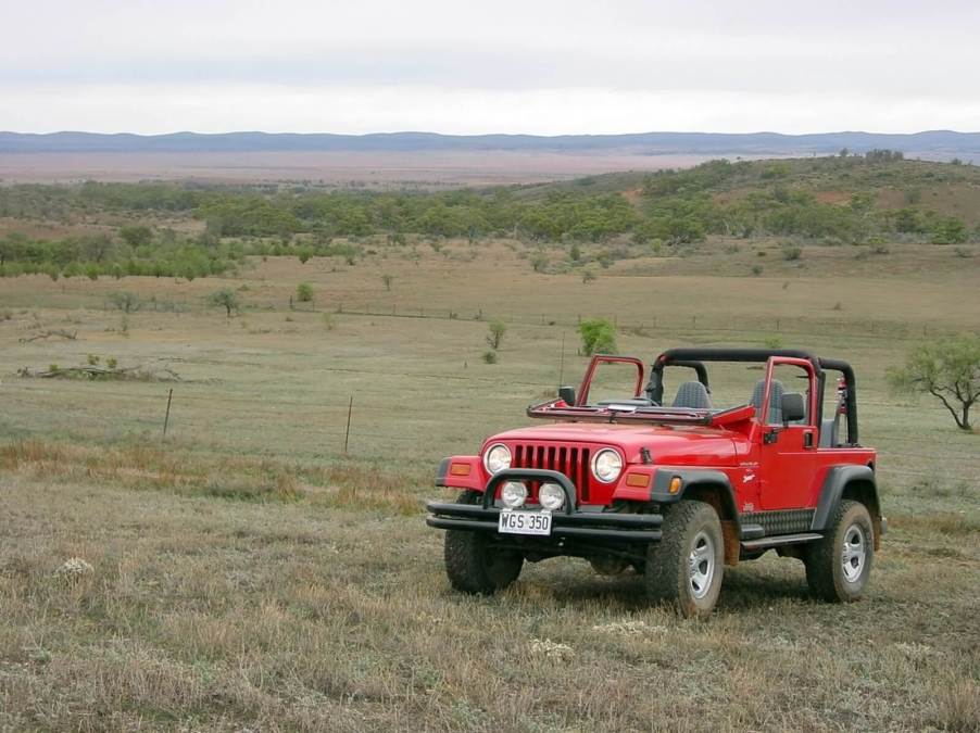 A bright-red Jeep Wrangler TJ with it a folded windshield.