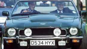 King Charles driving his gifted green Aston Martin V8 convertible with his body guard in 1988